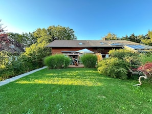 A house with a sloped roof, solar panels, and a well-maintained garden.