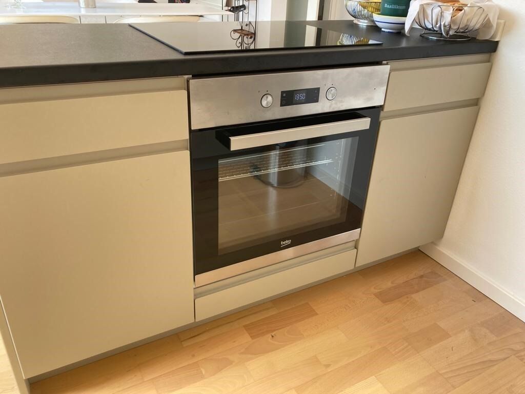 Een keuken met een inbouwoven, een digitale klok en een aanrechtblad van roestvrij staal.