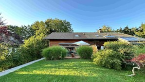 Uma casa com jardim, pátio e painel solar no telhado.