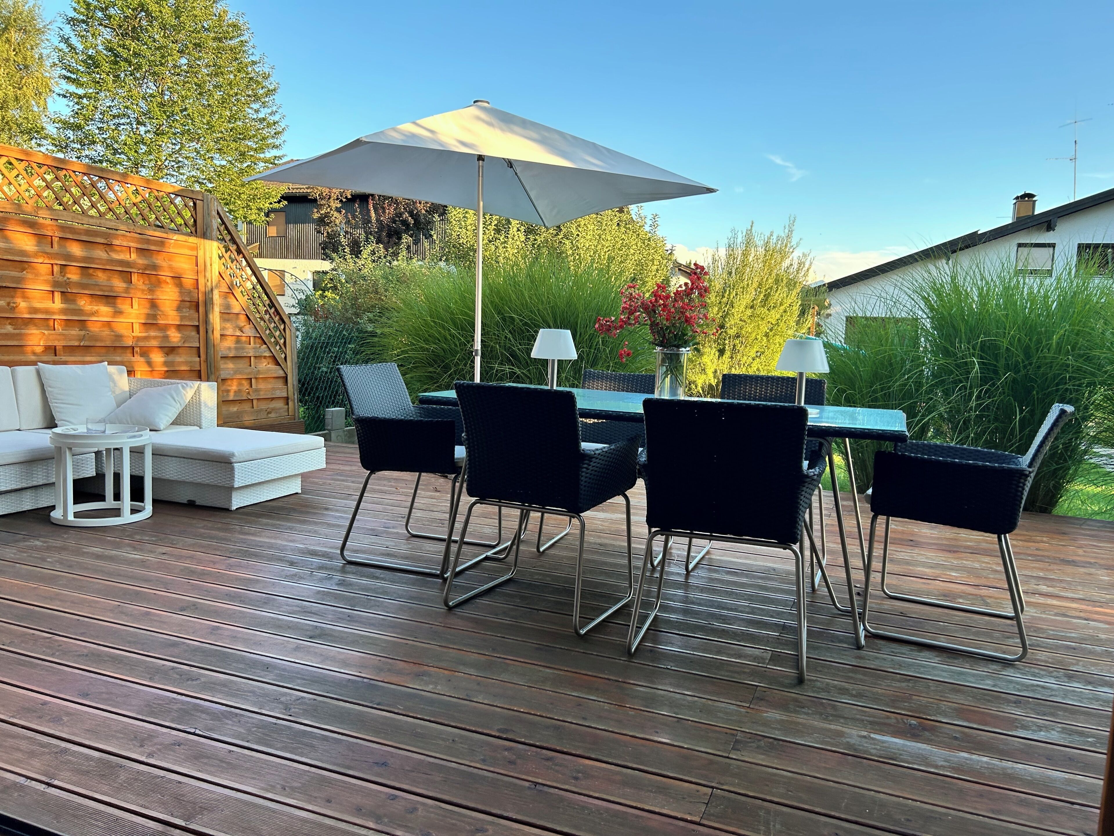 A deck with a dining table, chairs, and a sofa.