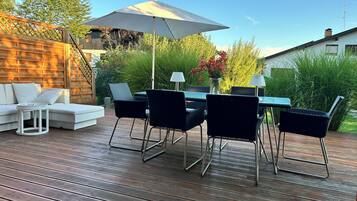 A deck with a dining table, chairs, and a sofa.