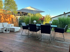 A deck with a dining table, chairs, and a sofa.
