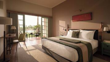 A hotel room with a large bed, a desk with a chair, a window with a view of palm trees, and a red artwork on the wall.