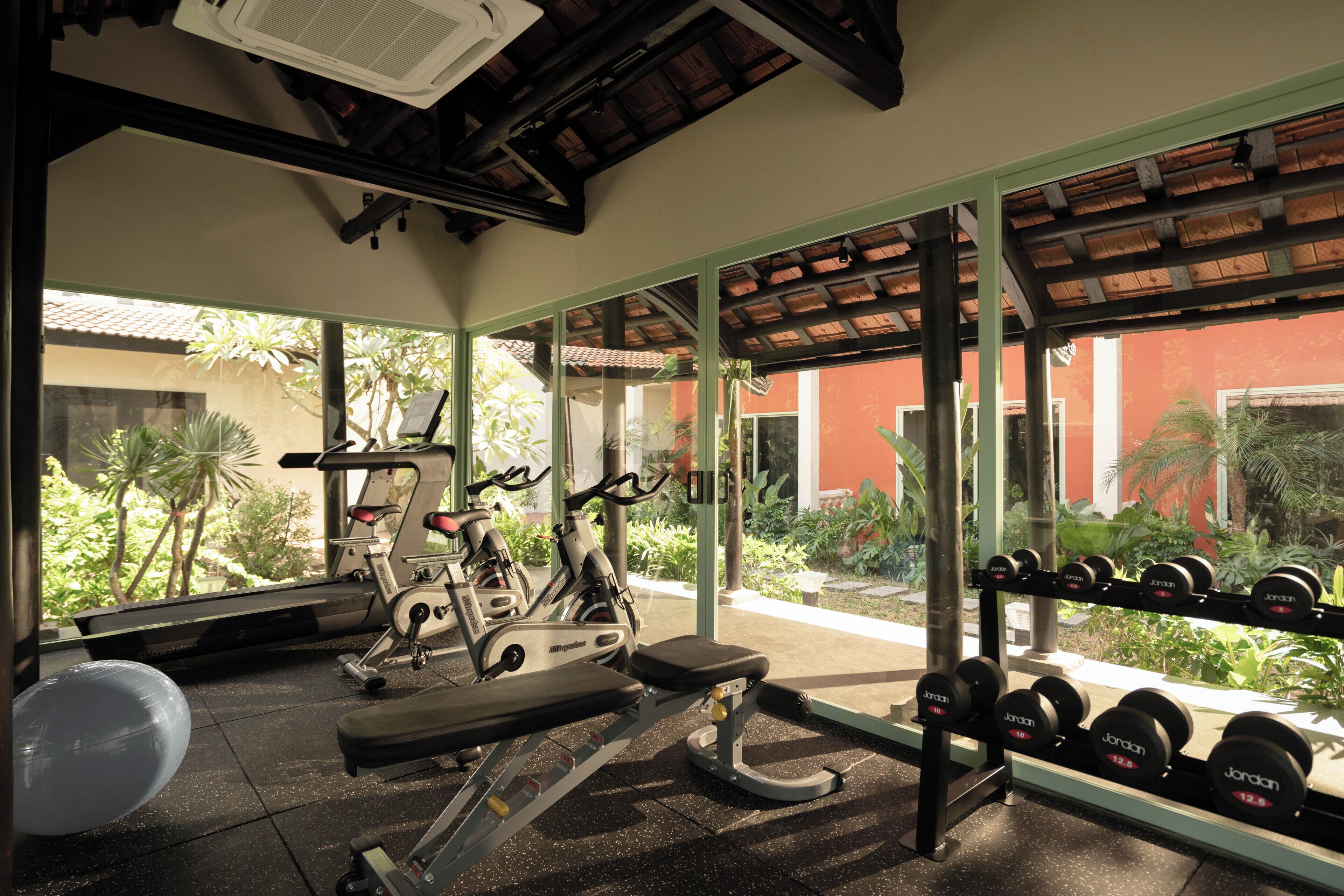 A gym with exercise equipment, a bench, and a rack of dumbbells.