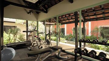 A gym with exercise equipment, a bench, and a rack of dumbbells.
