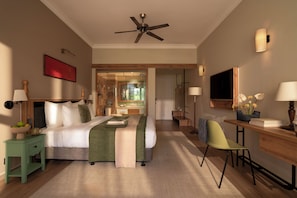 A hotel room with a bed, bedside table, desk, chair, and a ceiling fan.