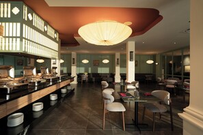 A restaurant with a buffet, seating area, and a large chandelier.