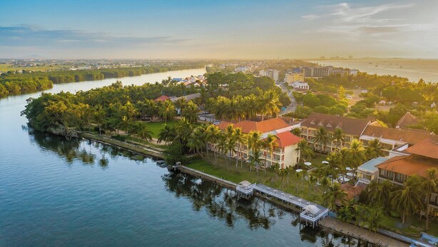A coastal hotel with a waterfront view, a dock, and a landscaped garden. - M Village Resort Riverbeach Hoi An (Da Nang)