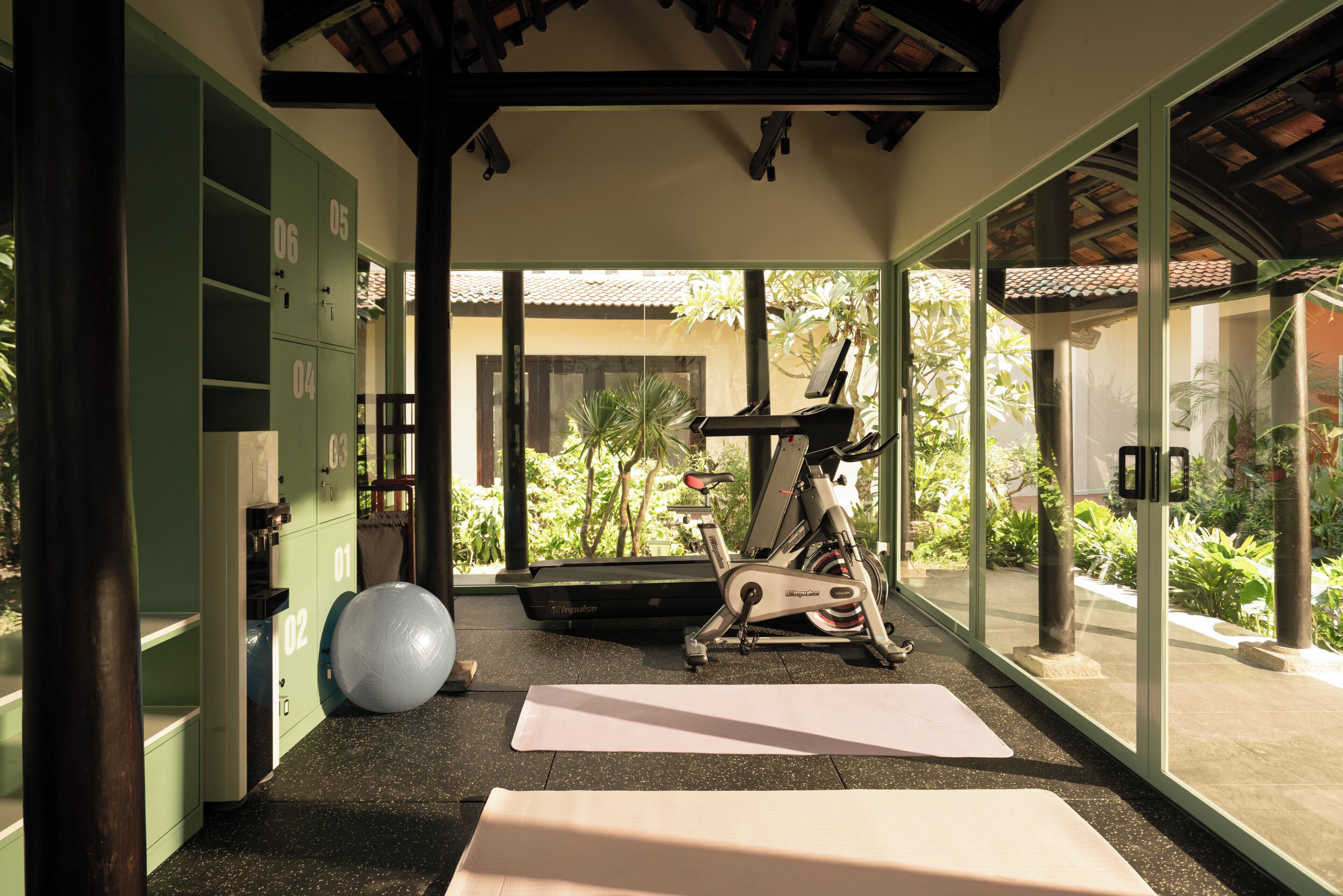 Un gimnasio en casa con equipo de ejercicio, una colchoneta de yoga y una pelota grande para ejercicios.