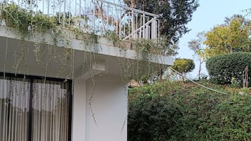 A modern house with a balcony, a bench, and a garden.