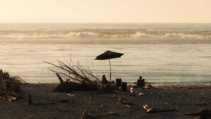 A beach scene with a tent, chairs, and an umbrella. - Rimu View 6 by Tiny Away (Ruatapu)