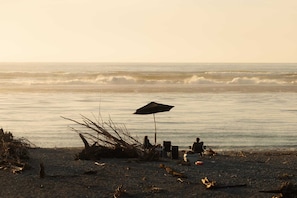 Eine Strandlandschaft mit Zelt, Stühlen und Sonnenschirm.
