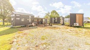 A modern, multi-unit residential complex with a gravel driveway and outdoor seating area. - Rimu View 6 by Tiny Away (Ruatapu)