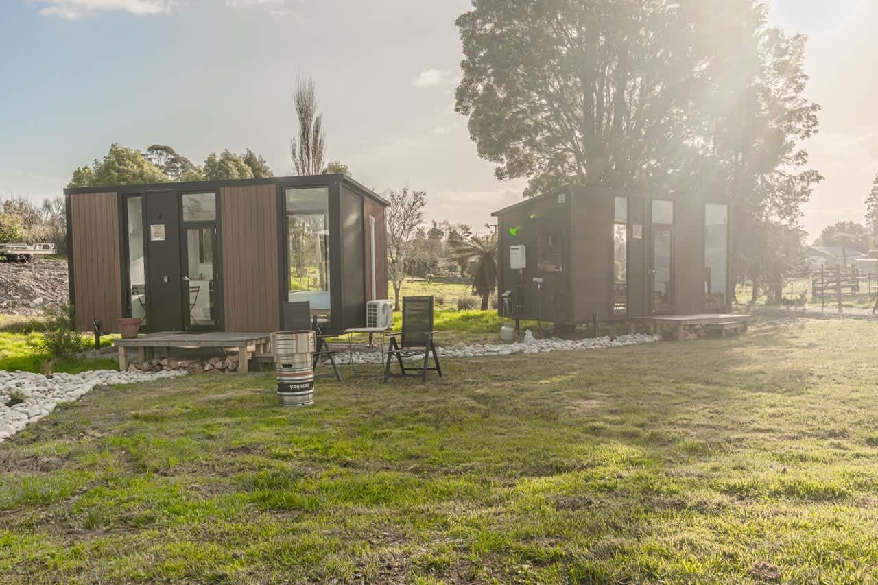 Two modern cabins with glass doors, a wooden deck, and outdoor seating.