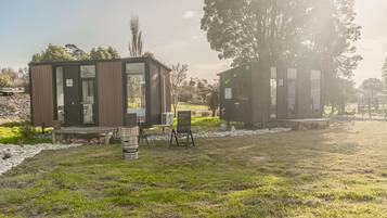 Two modern cabins with glass doors, a wooden deck, and outdoor seating.