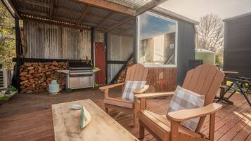An outdoor deck with a grill, chairs, and a table.
