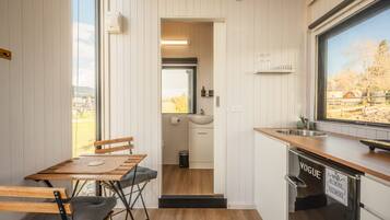 A compact kitchen with a wooden table and chairs, a sink, and a window with a view of the outdoors.