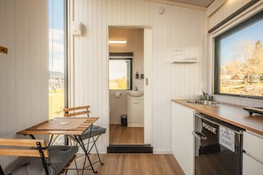 A compact kitchen with a wooden table and chairs, a sink, and a window with a view of the outdoors.