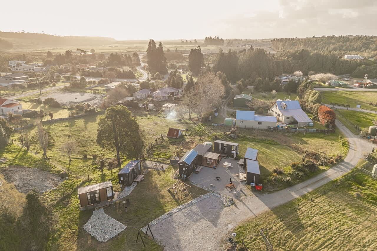 A rural landscape with multiple buildings, including a house with a large driveway and a barn.
