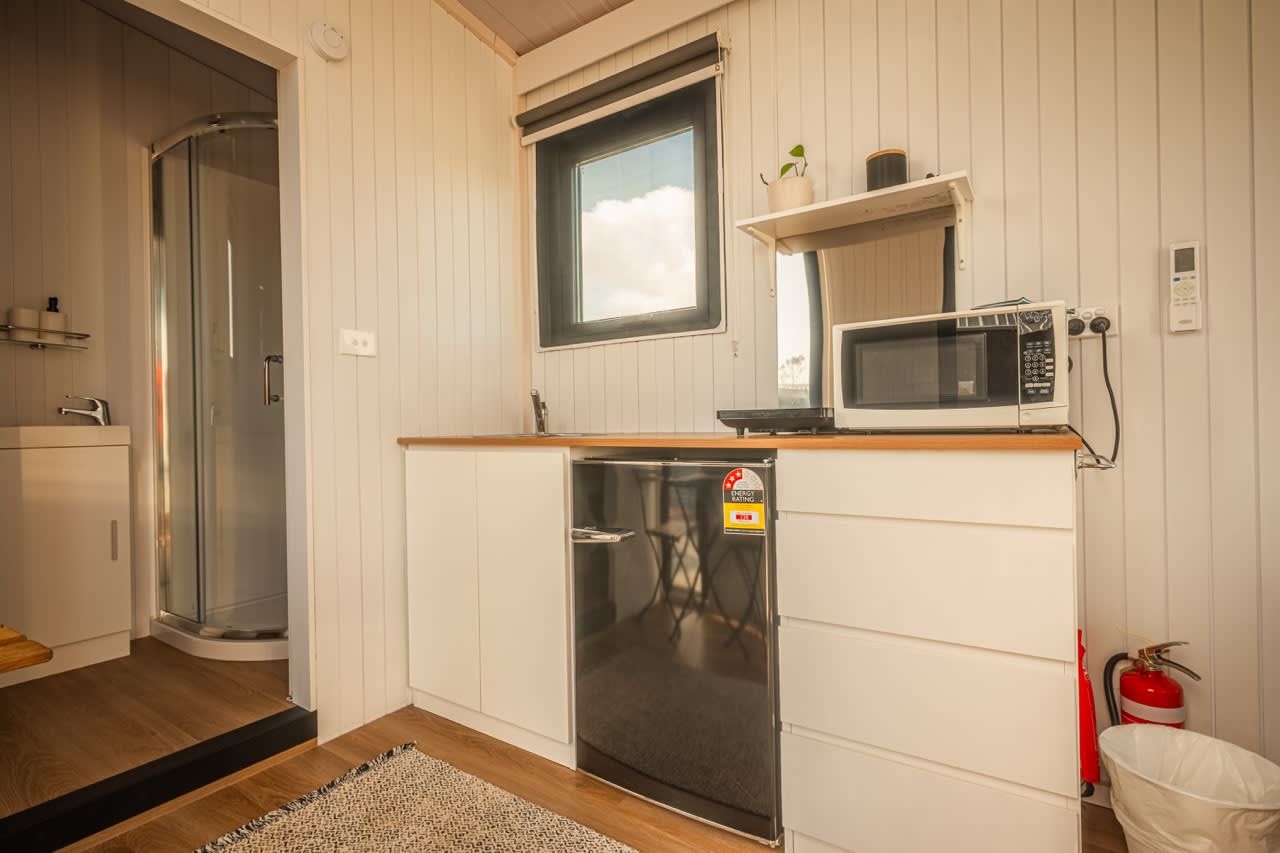 A compact kitchenette with a microwave, a small refrigerator, and a window above the sink.