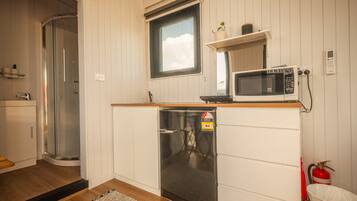 A compact kitchenette with a microwave, a small refrigerator, and a window above the sink.