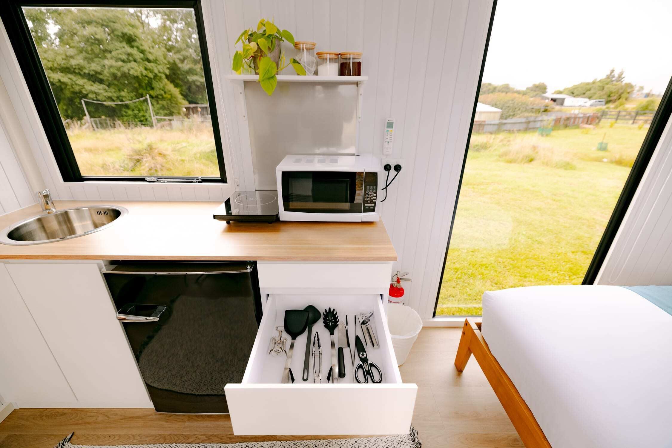 Cocina compacta con microondas, pileta y cajón de almacenamiento con utensilios.