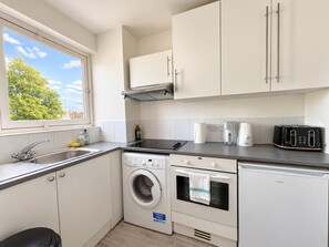 Een kleine keuken met een wasmachine, een koffiezetapparaat en een broodrooster.