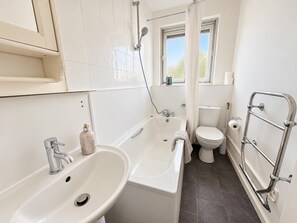Een badkamer met een wit wastafelmeubel, bad en toilet.