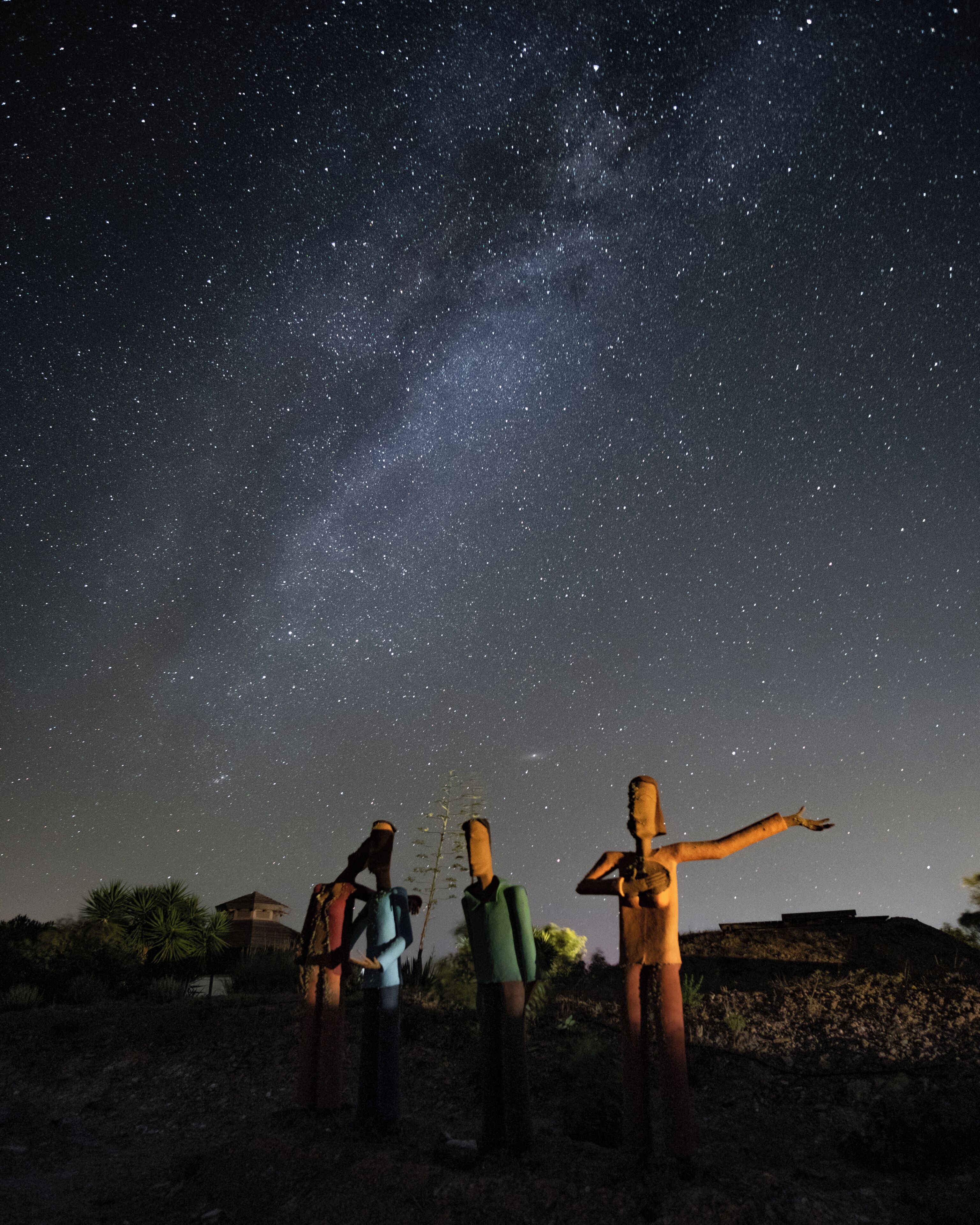 Three figures standing under a starry night sky.
