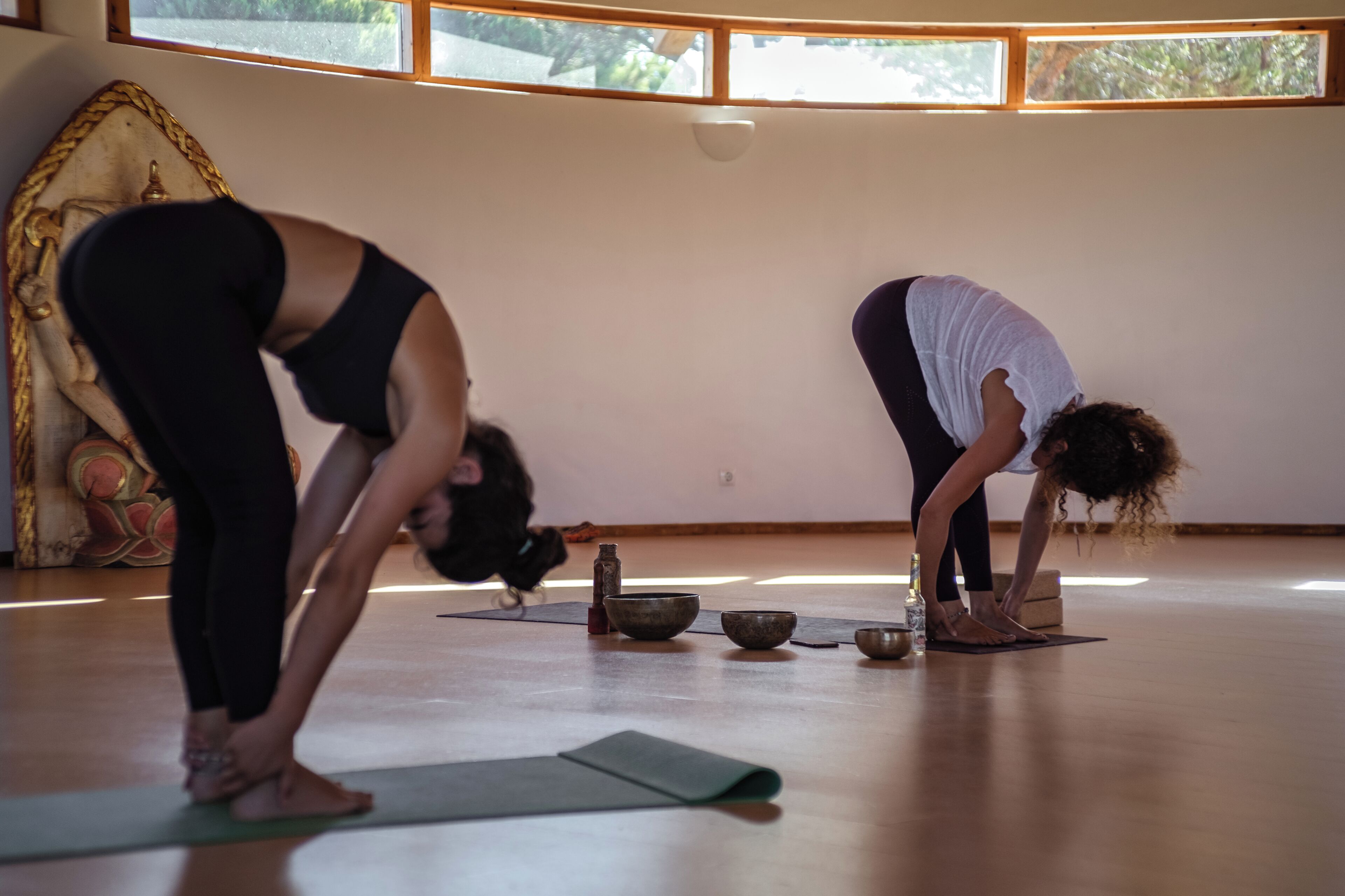 A yoga studio with mats, bowls, and a statue.