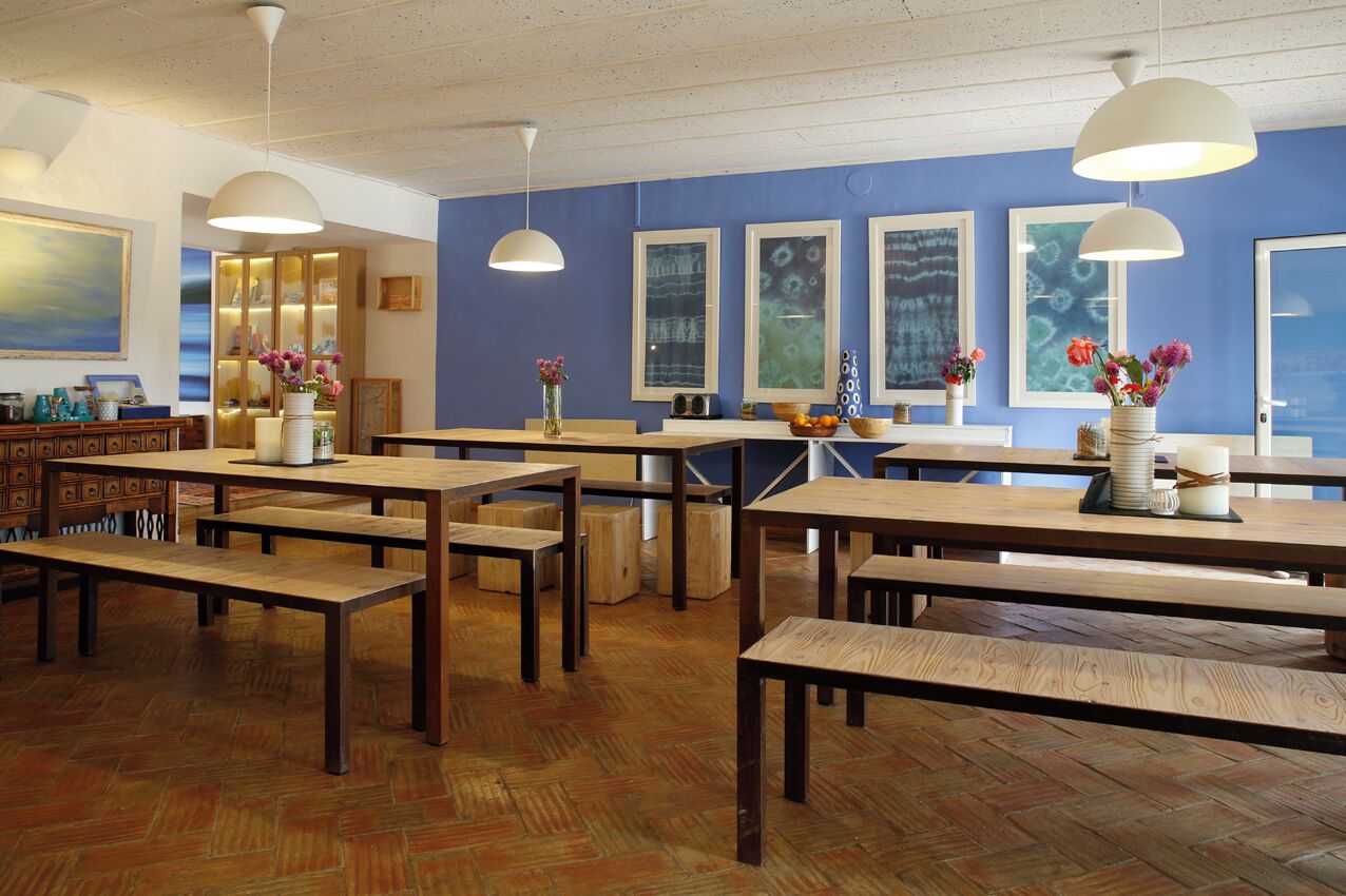 A restaurant with wooden tables and benches, blue walls, and artwork.