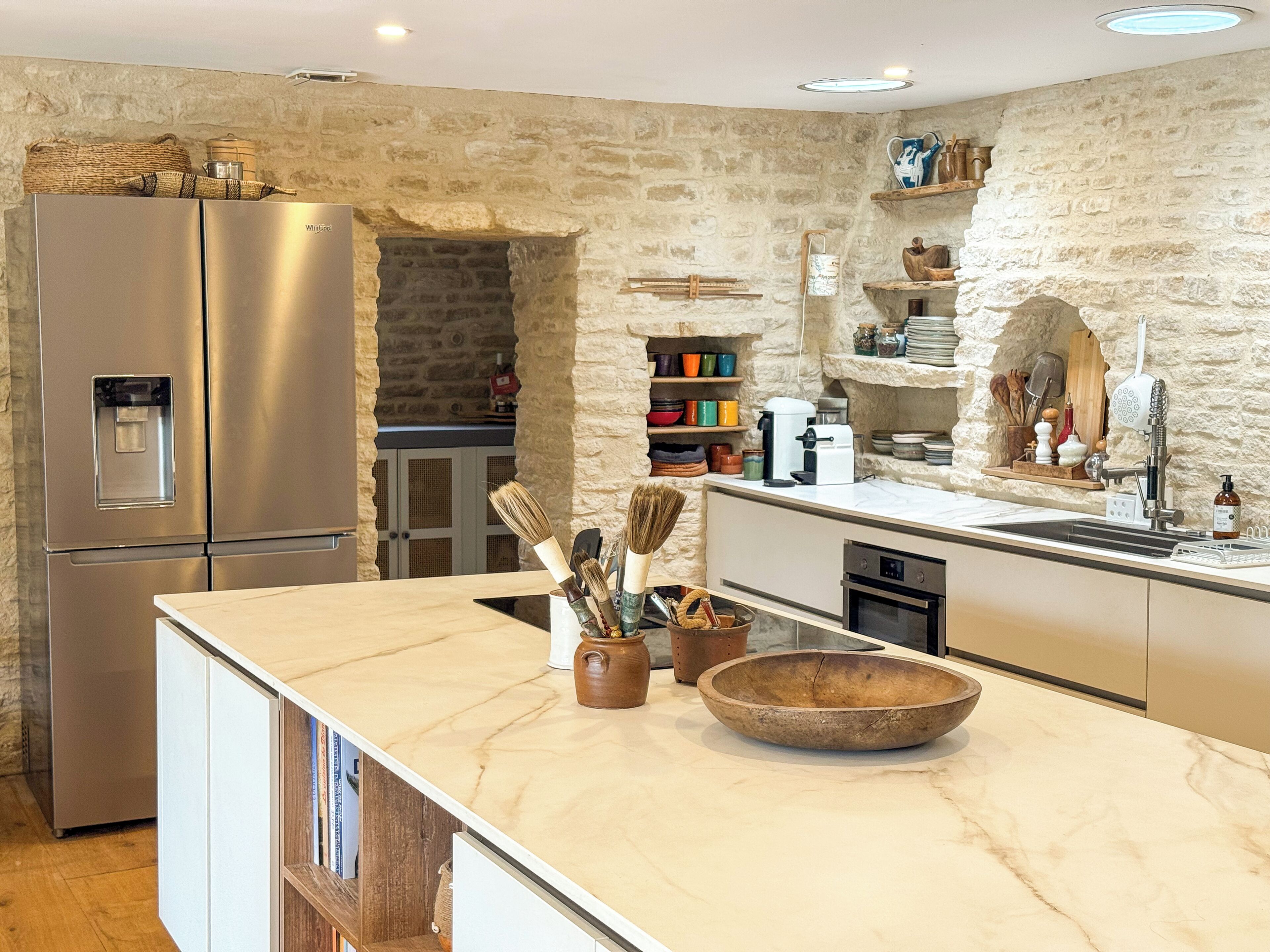 A modern kitchen with a stone wall, stainless steel appliances, and a marble countertop.