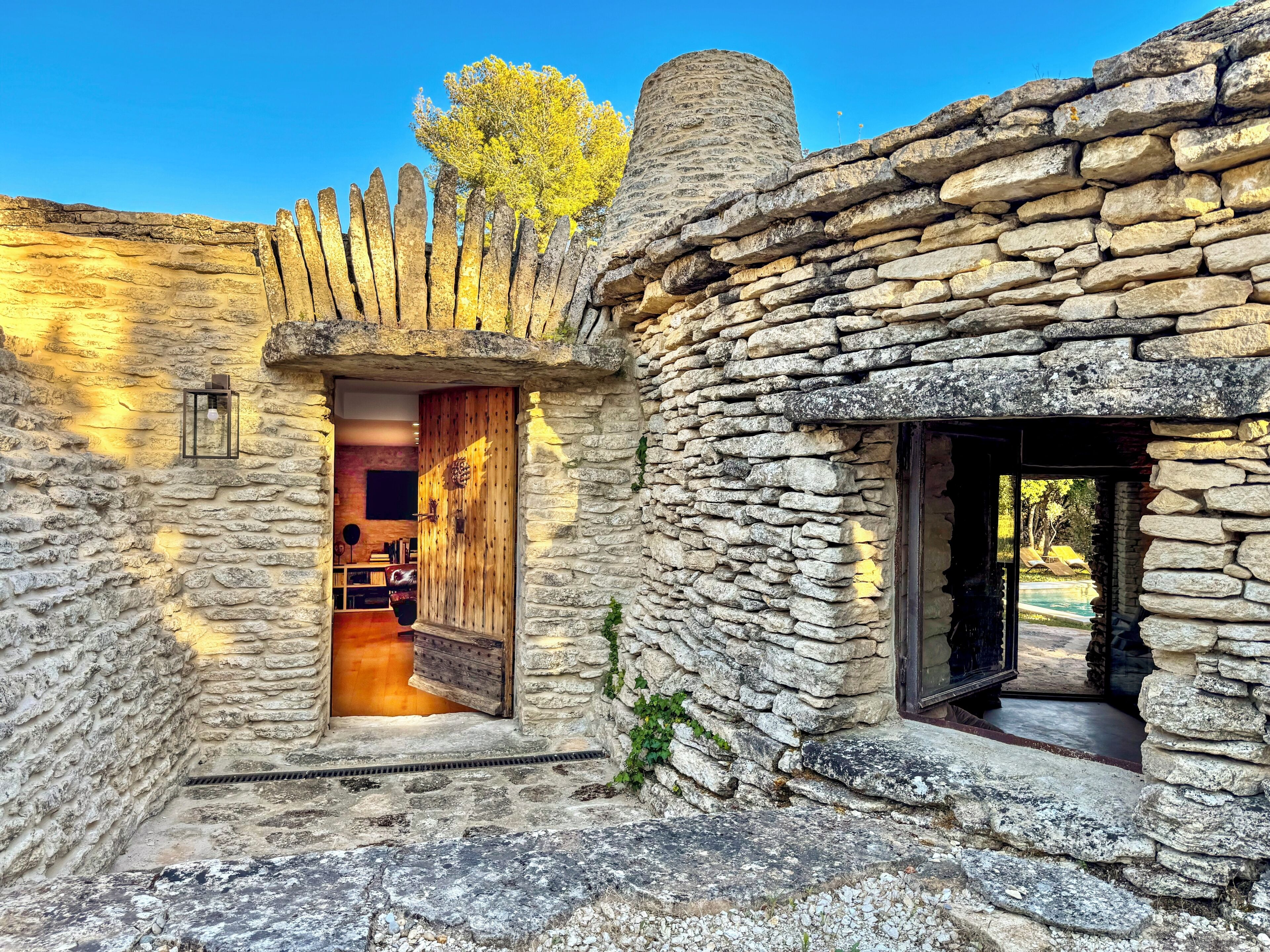 A stone building with a wooden door, a small window, and a stone wall.