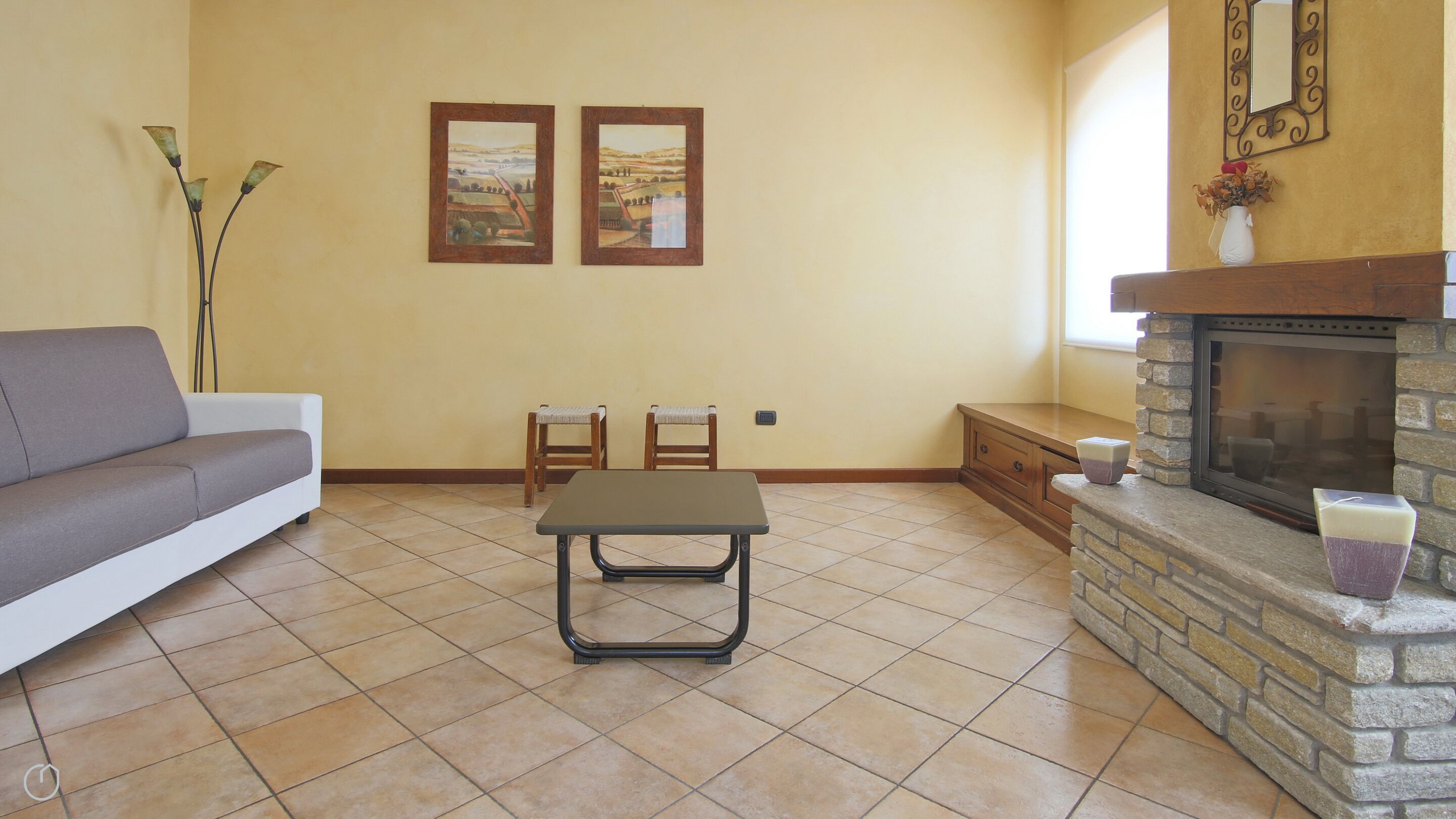 A living room with a sofa, two chairs, a small table, a fireplace, and two framed pictures on the wall.
