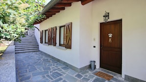 A stone staircase leading to a wooden door with a welcome mat. - Villetta Contrada by Wonderful Italy (Cerano D'intelvi)