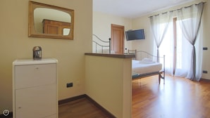 A bedroom with a bed, a TV, a mirror, a wardrobe, and a window with curtains. - Villetta Contrada by Wonderful Italy (Cerano D'intelvi)