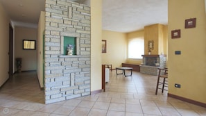 A spacious living area with a stone accent wall, a fireplace, and a dining table. - Villetta Contrada by Wonderful Italy (Cerano D'intelvi)