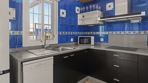 Une cuisine avec des carreaux bleus, un four à micro-ondes, un évier et des placards.