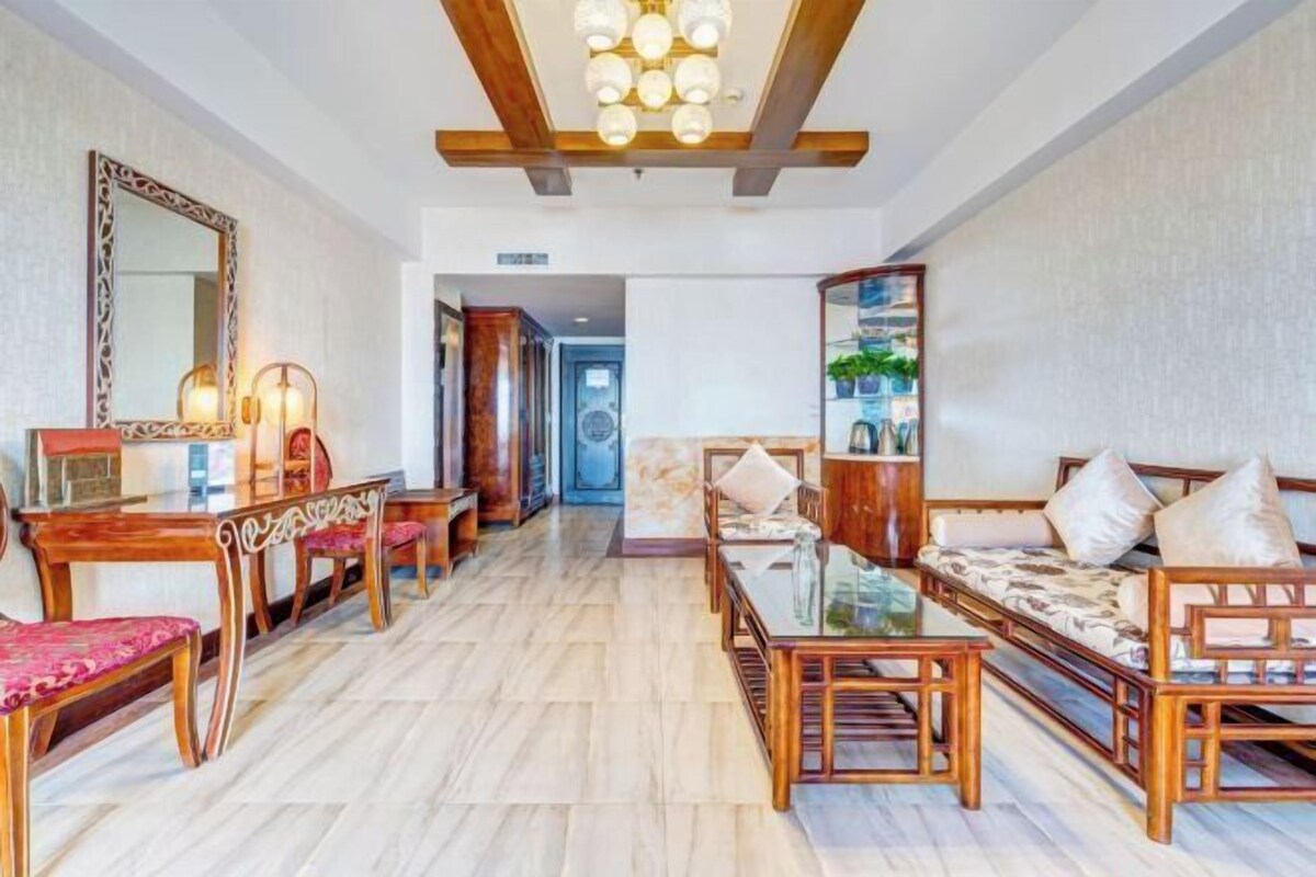 A hotel room with a dining area, a sofa set, and a large mirror.