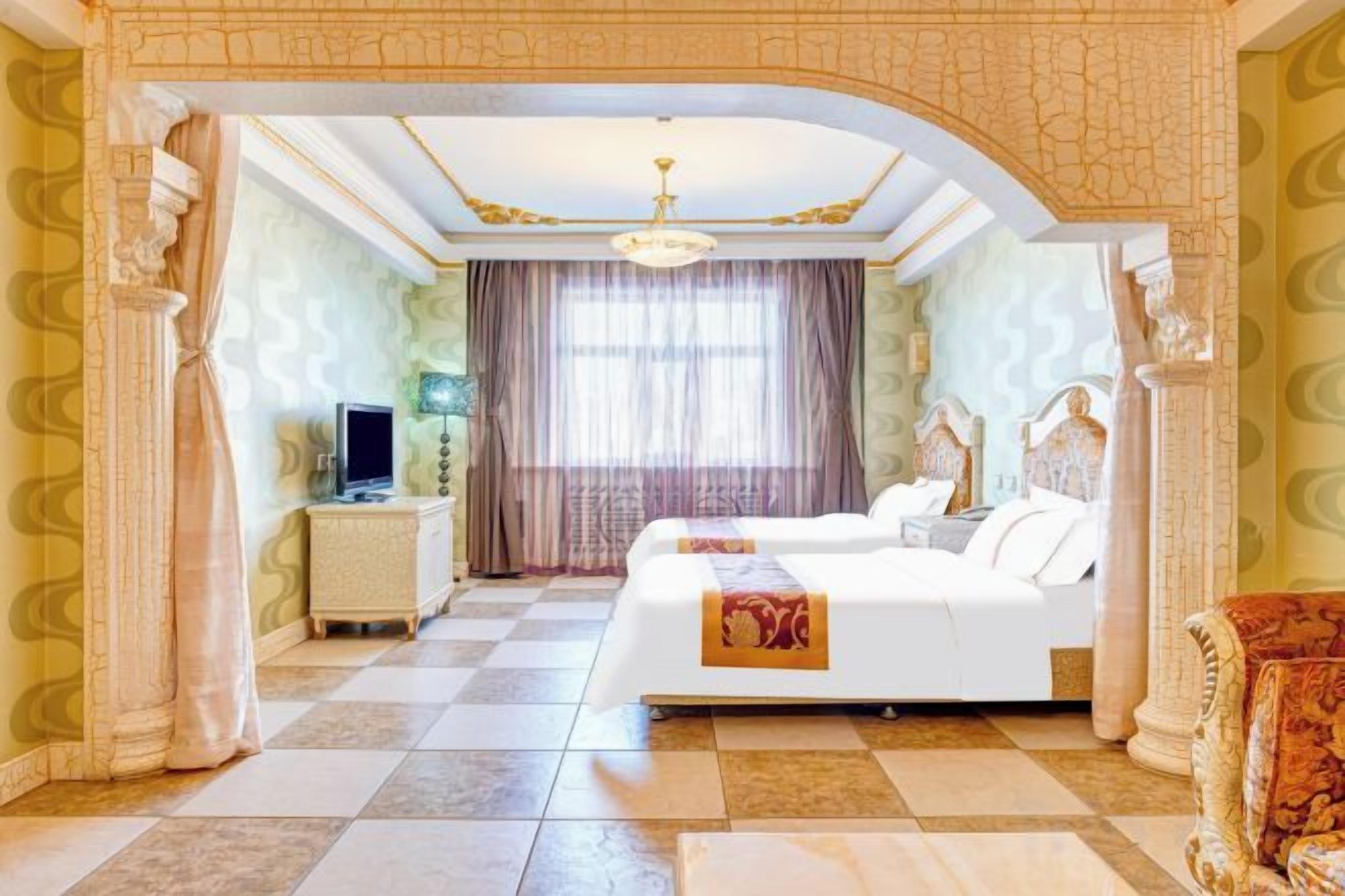 A hotel room with a checkered floor, a bed, a TV, and a chandelier.