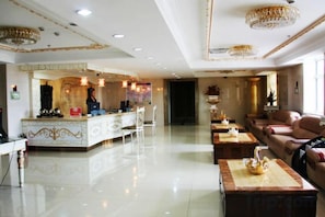 A spacious living area with a central bar, seating arrangements, and a chandelier.
