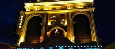 A large, illuminated building with arched entrances and signage indicating a hotel.
