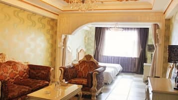 Una habitación de hotel con sofá, mesa de centro, cama y televisor.