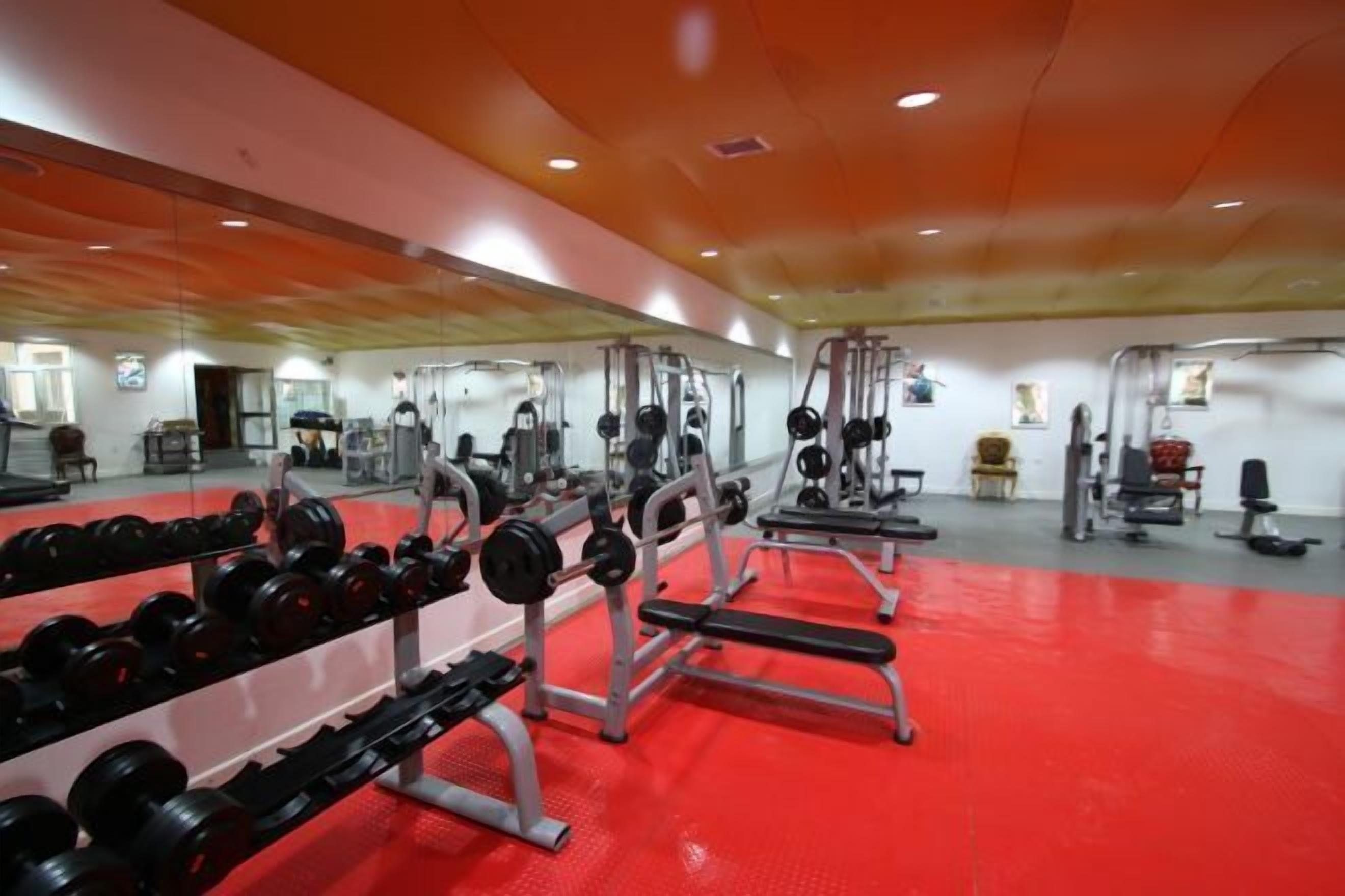 A gym with various exercise equipment, including dumbbells, benches, and weight machines.