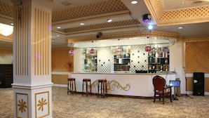 A bar area with stools, a counter, and a decorative ceiling. - Manzhouli Junyu Grand Hotel (Manzhouli Wanda Plaza Matryoshka Square) (Manzhouli)