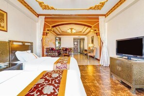 A hotel room with a large bed, a TV, and a dining area in the background. - Manzhouli Junyu Grand Hotel (Manzhouli Wanda Plaza Matryoshka Square) (Manzhouli)