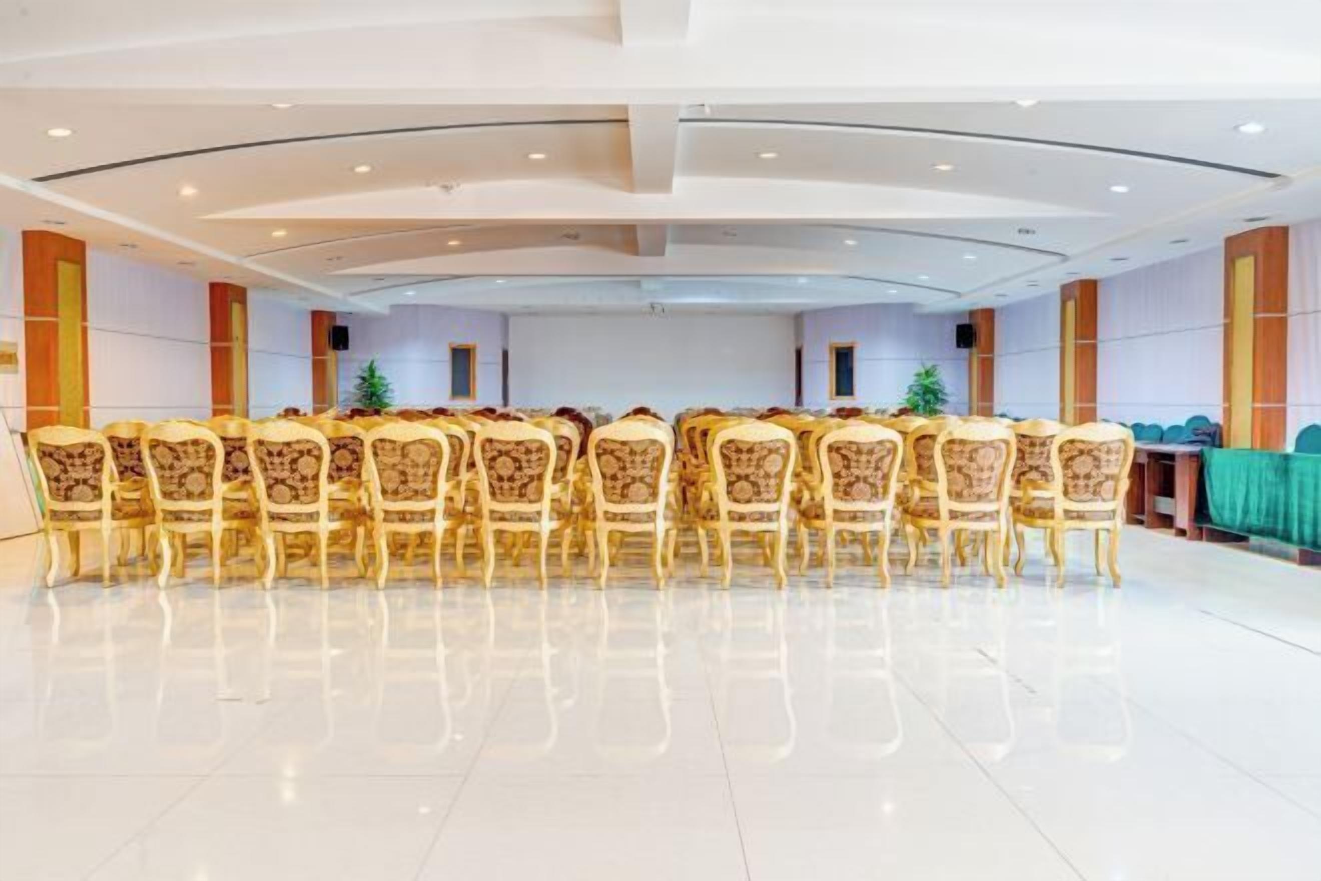 Una sala de conferencias con una larga mesa y sillas, un mantel verde y un árbol de Navidad.