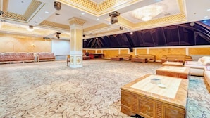 A spacious hotel lobby with a patterned carpet, seating areas, and a large screen. - Manzhouli Junyu Grand Hotel (Manzhouli Wanda Plaza Matryoshka Square) (Manzhouli)