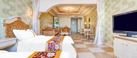 A hotel room with two beds, a television, a dining area, and a bathroom.