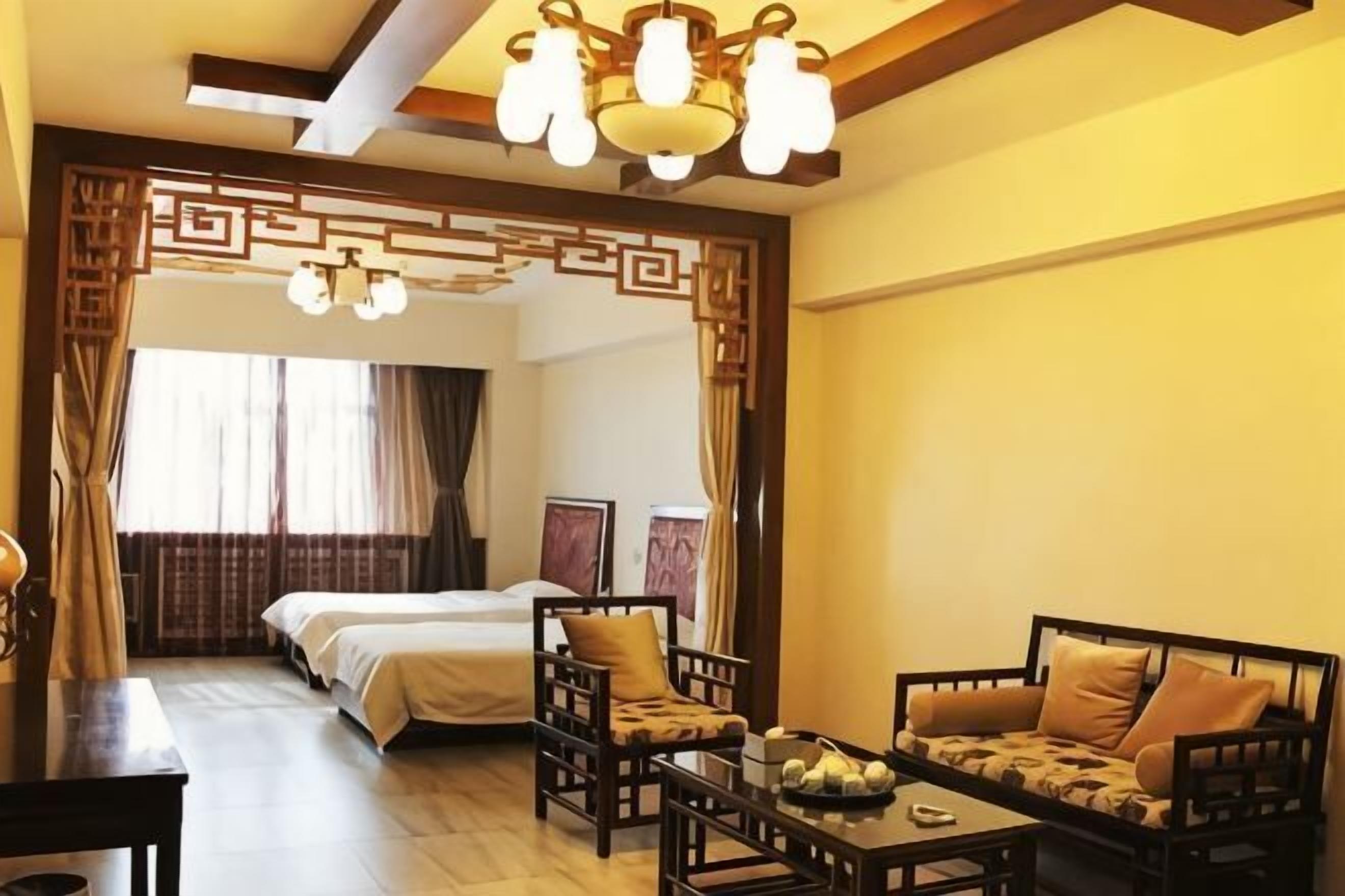 A hotel room with a bed, a sofa, a dining table, and a chandelier.